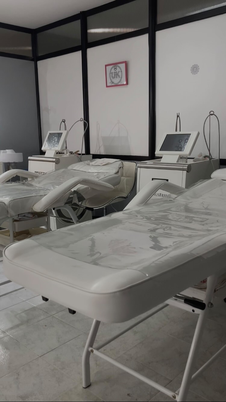 Una cabina de Bella con dos equipos Venus Freeze y sus camillas, detrás de las mamparas vidriadas